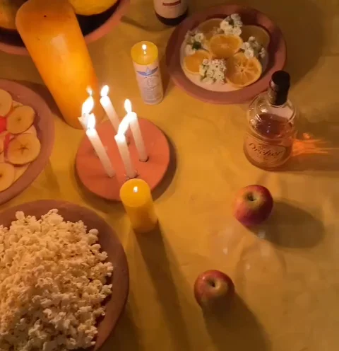 Mesa de oferenda preparada por Mãe Iracema, com velas acesas, flores e frutas